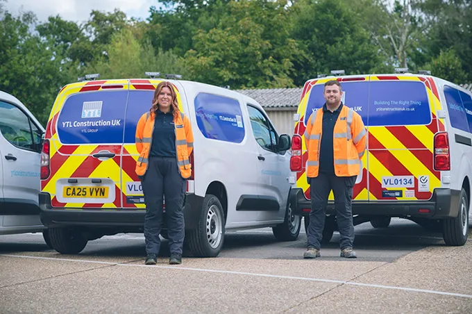 Two employees standing in front of company vans